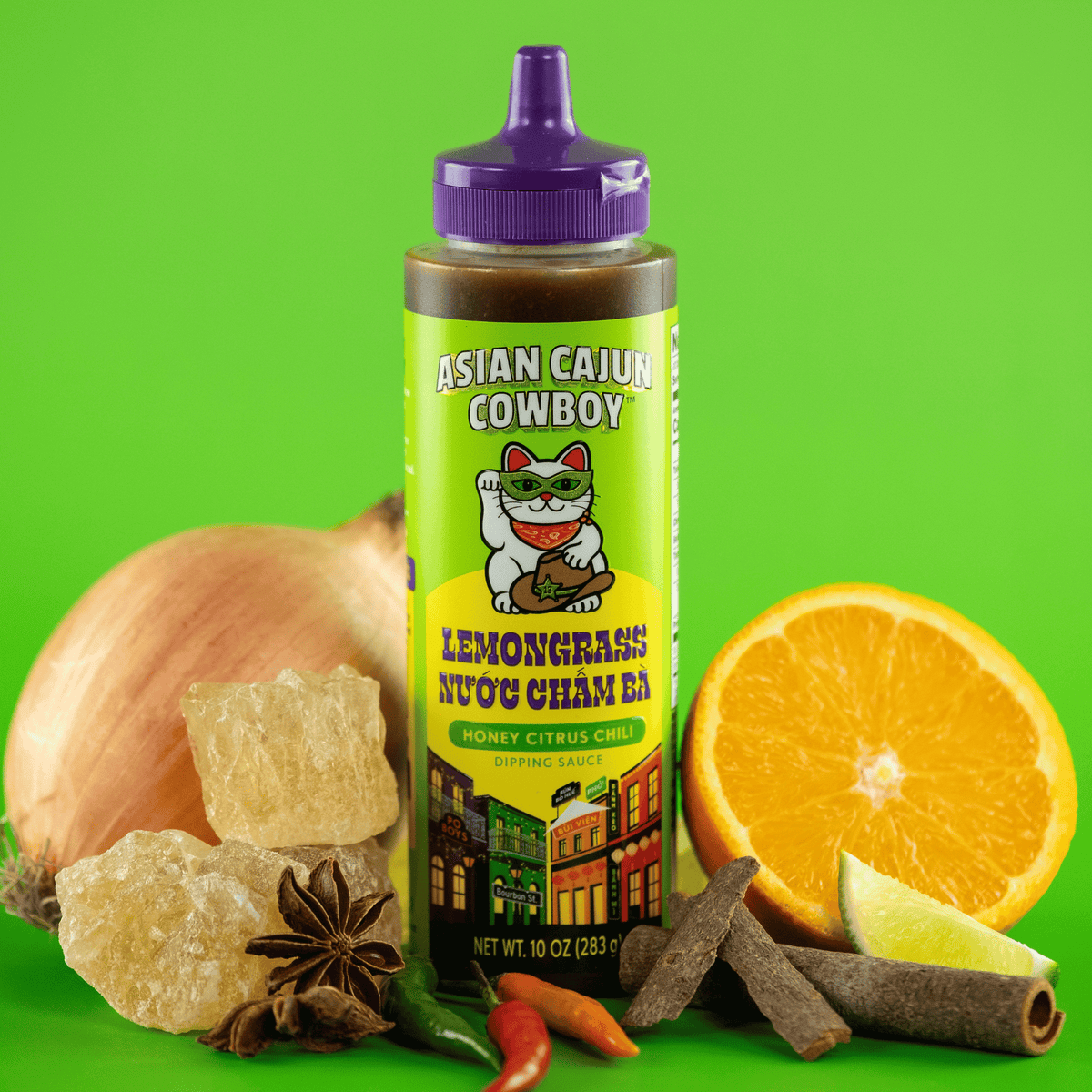 Asian Cajun Cowboy Lemongrass Nuoc Cham Ba dipping sauce bottle surrounded by ingredients on a green background.