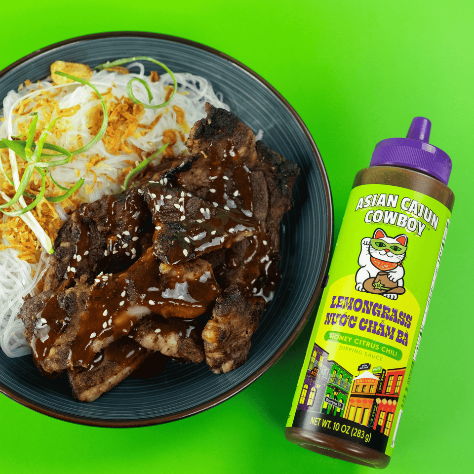 Lemongrass bottle next to a beef bowl on a green background