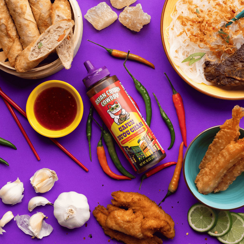 Cajun Nuoc Cham dipping sauce surrounded by asian cuisine on a purple background. 