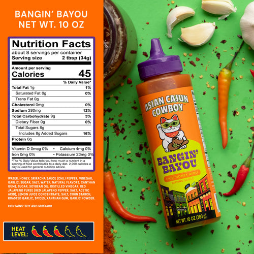Bottles of 'Asian Cajun Cowboy' Bangin' Bayou dipping sauce with nutrition label on a green background.